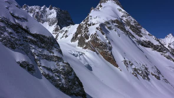 Drone flight over incredible epic mountain landscape winter snow covered sharp peaks of many rocks