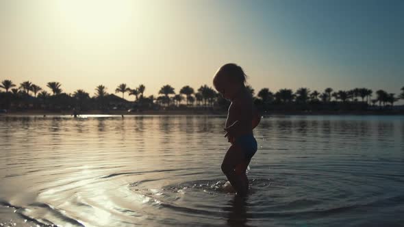 Cute Toddler Walking in Seawater at Beach. Little Child Playing at Seaside. alt