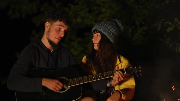 Young couple singing and playing guitar alt