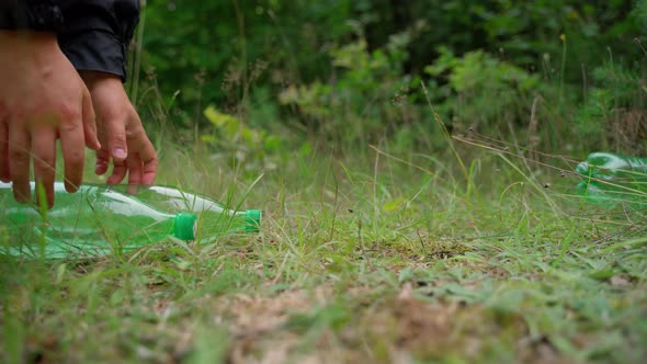 Save and rescue planet from global pollution concept. Man hand remove plastic bottles from meadow alt