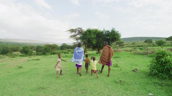 Maasai family walking on a field alt