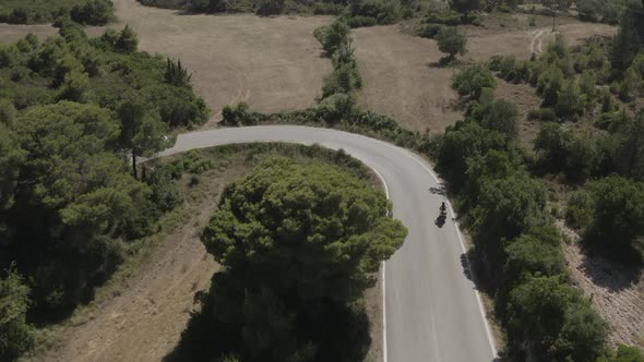 Aerial Shot of a Scooter Moving in the Curvy Road in the Green Hills