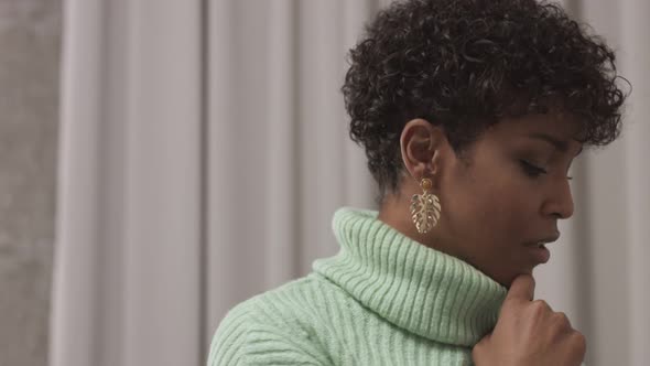 Woman in Mint Sweater in Studio with Grey Curtain Background alt