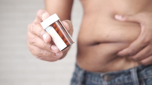 Holding Excessive Belly Fat and Pill Container with Copy Space alt