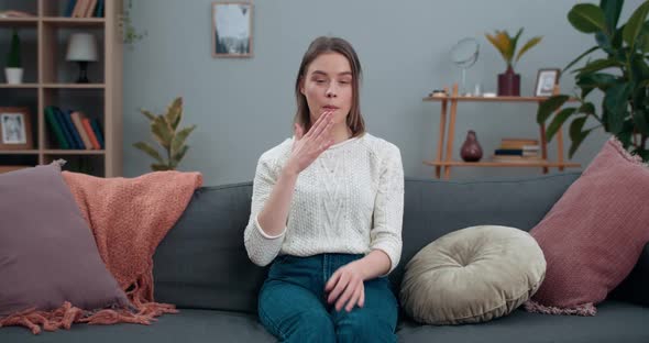 Cheerful Millennial Woman Saying Nonverbal Phrase I Hear It with My Heart While Sitting on Sofa alt