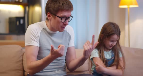 Angry Father Sitting with Little Stubborn Daughter and Scolding for Bad Behavior alt