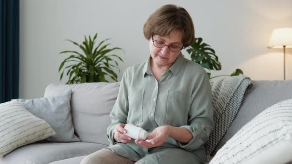 Senior Adult Woman Holding Painkiller Pills on Female Hand Pouring Capsules From Medical Bottle alt