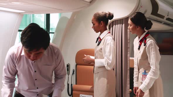 Two stewardesses checking boarding pass their passengers. Multiracial passengers boarding the plane