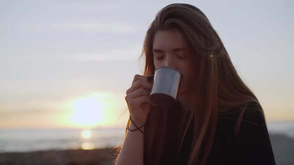 Closeup Beautiful Long Haired Woman Cautiously Drinking Hot Coffeee From Metal Cup on Nature Early alt
