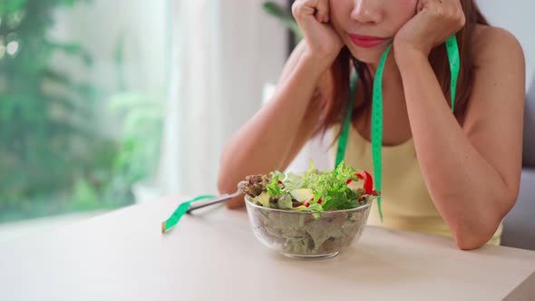 Young woman boring while eating fresh vegetable at home