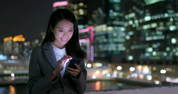 Businesswoman use of cellphone in city at night alt