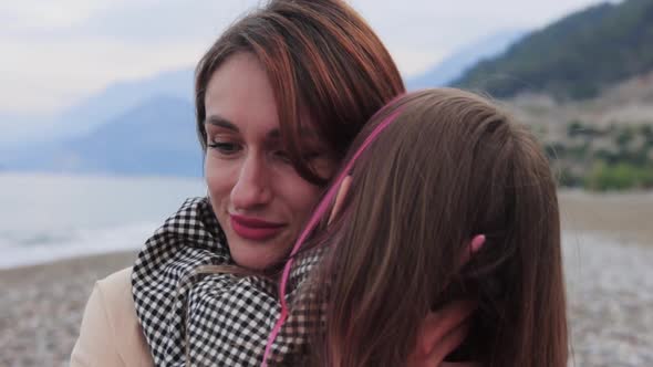 Mother Hugging with Her Little Daughter By the Sea alt