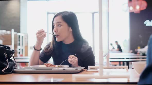 Asian woman sitting separated in restaurant eating food .keep social distance alt