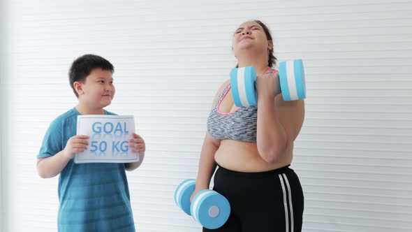 Son obesity encouraging Fat mother while lifting dumbbells exercise for diet