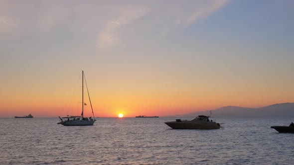 Sunset in Mykonos, Greece with and Yachts in the Harbor alt