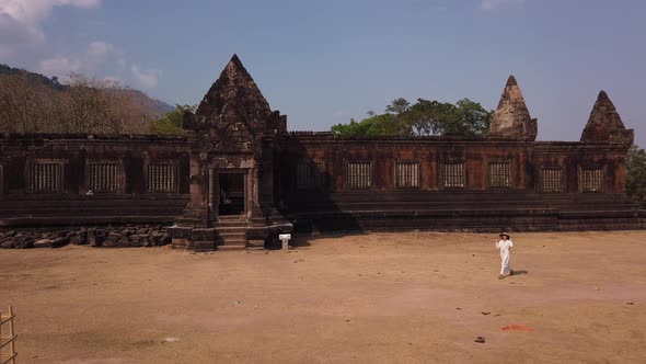 Woman in vietnamese hat walk near ancient Khmer palace Vat Phou ruined Hindu Temple Laos, Asia, Slow alt