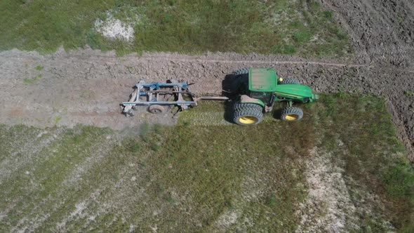 A tractor plowing a field in Brazil on land deforested from the Amazon rainforest - aerial view alt