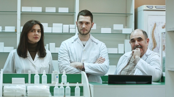 Positive team of pharmacists looking at camera at the hospital