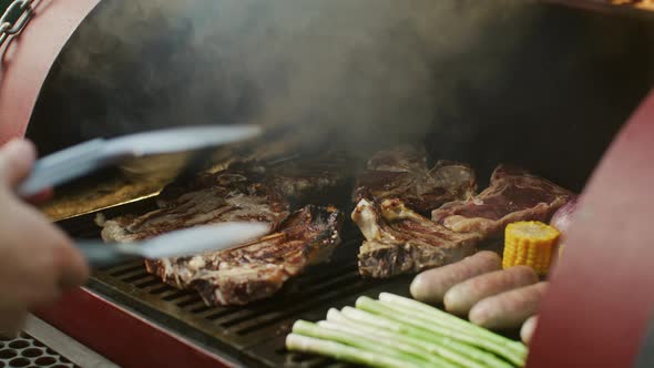 Chef Turns Meat on Grill with Tongs