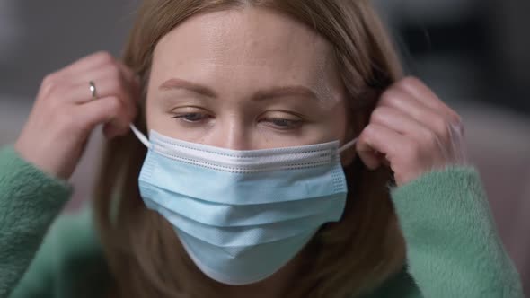 Headshot Tired Young Woman Taking Off Covid Face Mask Sighing Looking at Camera alt