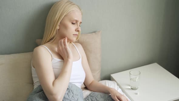Unhappy Woman Taking a Pills and Drinking Glass of Water alt