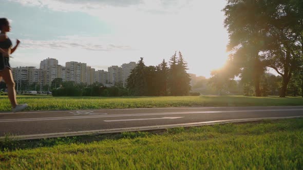 Free Young Woman Runs in Summer Park at Sunset