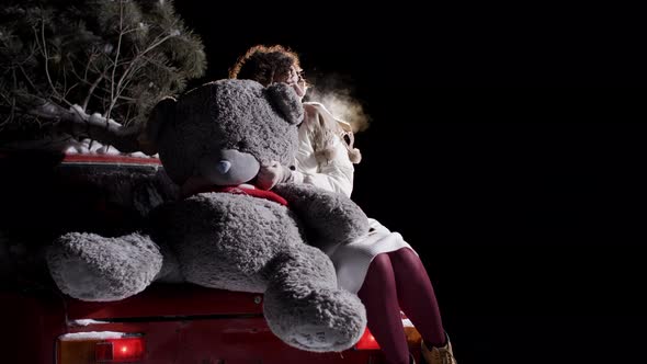 Beautiful Girl Big Teddy Bear on New Year Car in Night Moon Light alt