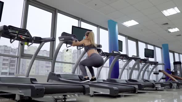 Young sporty Woman On Running Machine In Gym alt