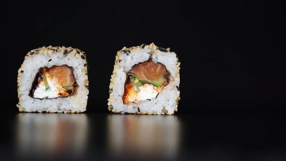 Sushi Rolls Are Lifted Up with Chopsticks in Sequence. Japanese Food. Black Background.