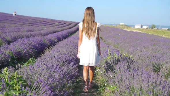 Woman in Lavender Flowers Field at Sunset in White Dress and Hat