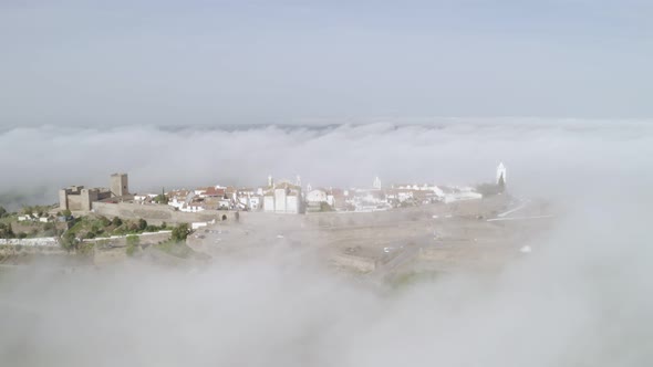Aerial drone view of Monsaraz on the clouds in Alentejo, Portugal alt
