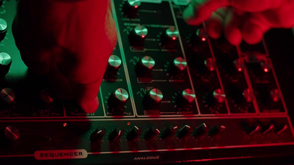 slow motion macro shot of a man turning knobs on a vintage synth, dark red and green ambiance alt