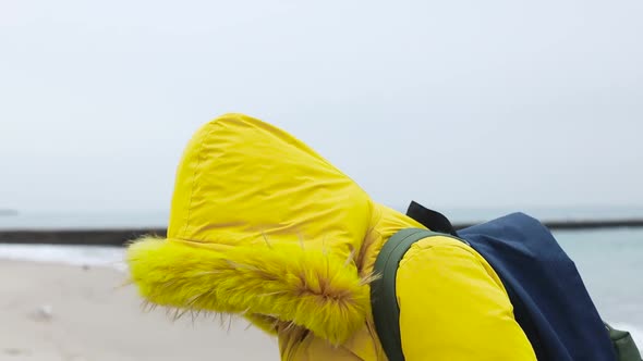 Adult Woman in a Warm Yellow Jacket with a Backpack Uses a Protective Medical Mask Walking Walks alt