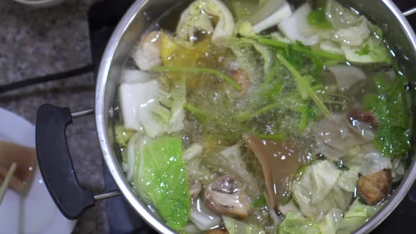 Chinese Style Clear Soup Hot Pot With Vegetable And Seafood Eating Together With Chopsticks