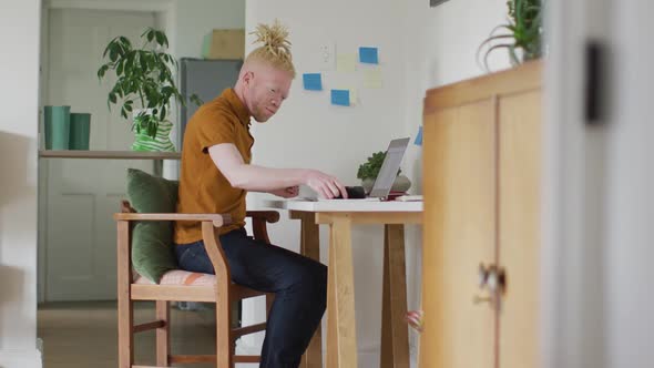 Albino african american man with dreadlocks working, using laptop and smartphone alt