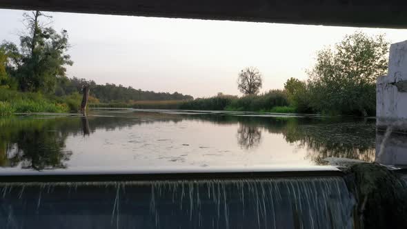 Small dam on the river with water flowing rapid.