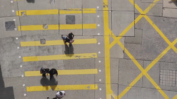 People crossing the yellow pedestrian crossing in Hong Kong - top view alt