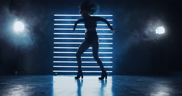 Silhouette Figure of a Dancing Girl in the Dark on Heels and Short Shorts alt
