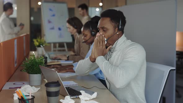 Unhealthy Man Sneezing While Working on Laptop in Office alt