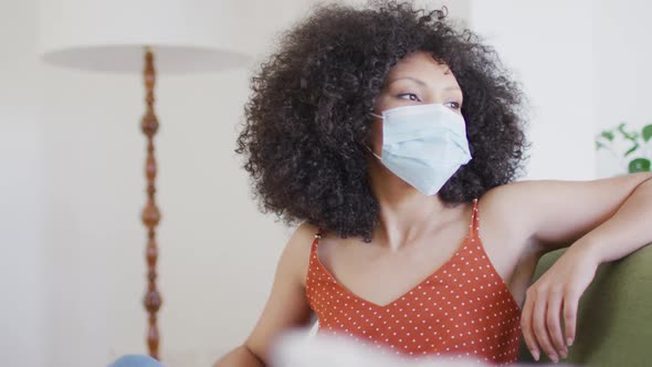 Woman wearing face mask sitting on the couch at home alt