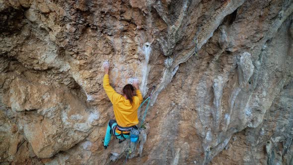 Skilful Athletic Male Rock Climber Resting While Climbs on Overhanging Rock Cliff alt