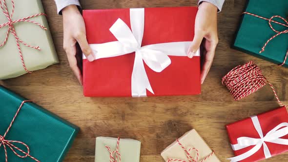 Woman hands giving a Christmas gift wrapped in red paper