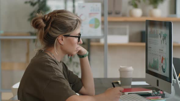 Businesswoman Analyzing Graphs on Computer in Office alt