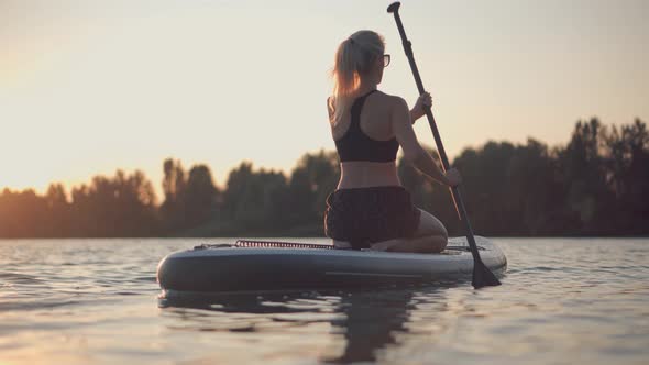 Girl Floating On Sup Board At Idyllic Evening. Swimming On Stand Up Paddle Board. Surfer Water Sport alt