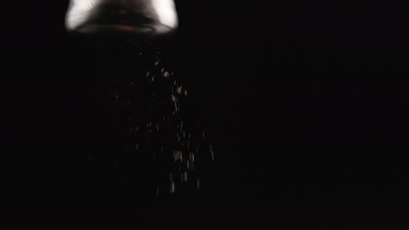 Black Pepper Falling Out From Pepperpot on Black Background in Slomo alt