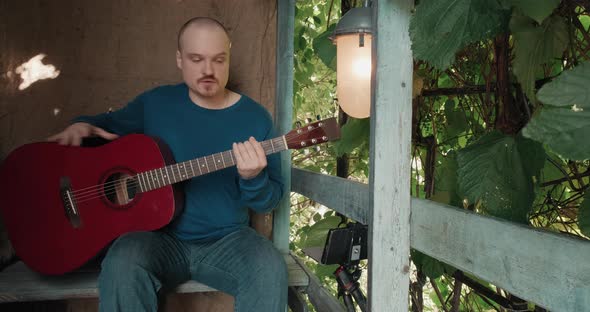 Man Leads an Online Acoustic Guitar Lesson From the Porch of His Suburban Farm