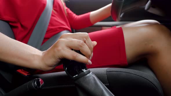 Woman in Red Dress Sitting Inside of Vehicle and Shifts Gearbox in a Car alt