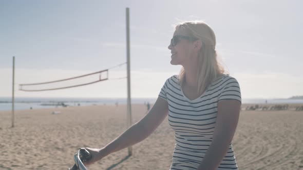 Young Adult Female Tourist cycling on beach in summer