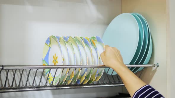Woman Takes Dishes From A Shelf. Plates In The Kitchen. Dishes