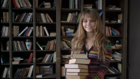 Young Beautiful Girl Holding a Stack of Books